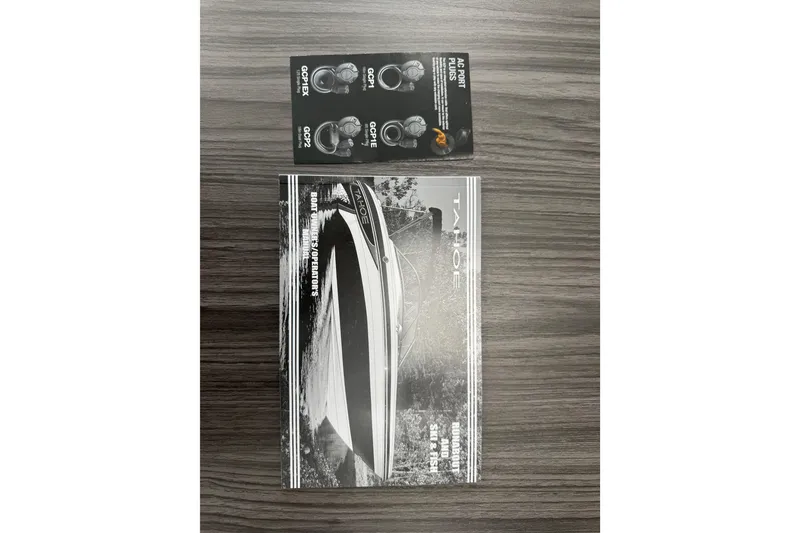 Slide: The Image of 2024 Tahoe 185 S boat brochure on wooden table with earbud packaging. - 91