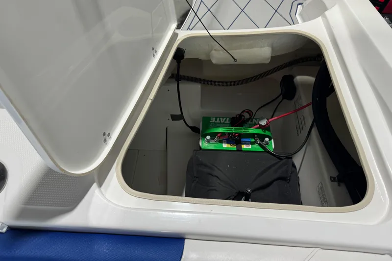 Slide: The Image of Open storage compartment in 2024 Tahoe 185 S boat, revealing battery and wiring. - 99