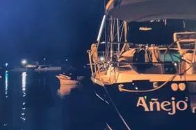 Slide: The Image of 2006 Beneteau 373 sailboat named "Añejo" docked at night with lights reflecting on water. - 13