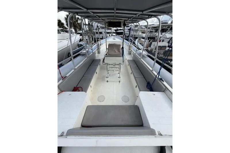 Slide: The Image of 2009 Eduardono RIB boat interior with seating and canopy, docked at marina. - 10