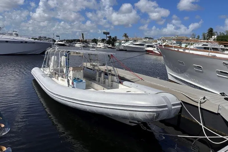 Slide: The Image of 2009 Eduardono RIB boat docked in a marina, surrounded by yachts under a blue sky. - 7