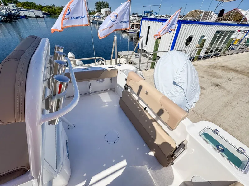 Slide: The Image of 2025 Edgewater 208CC boat interior with seating, docked at marina with flags. - 7