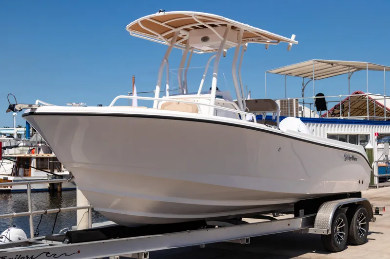 Slide: The Image of 2025 Edgewater 208CC boat on trailer at marina, clear blue sky background. - 1