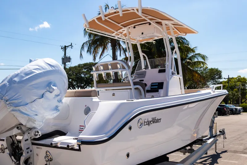 Slide: The Image of 2025 Edgewater 208CC boat with canopy, parked outdoors under clear sky. - 6