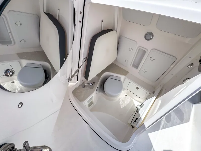 Slide: The Image of 2025 Edgewater 262CC boat interior with compact marine toilet and storage compartments. - 17