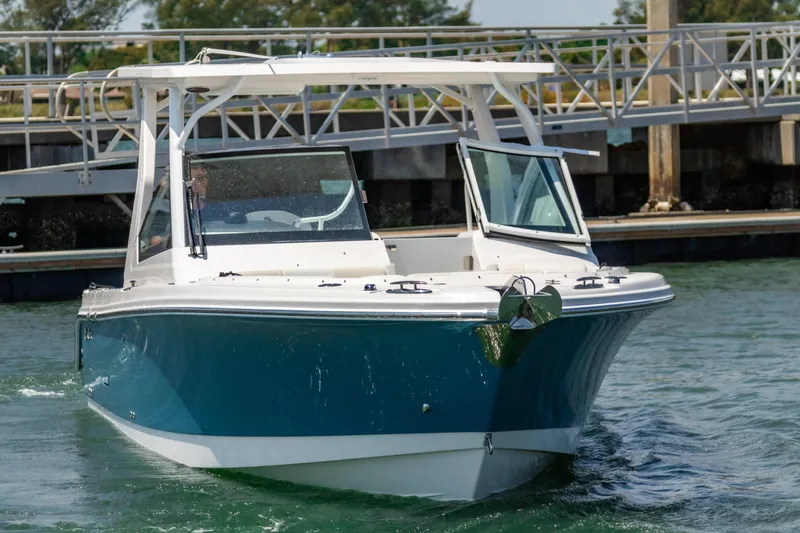 Slide: The Image of 2025 Edgewater 262 CX boat cruising near a dock, featuring a sleek blue and white design. - 3
