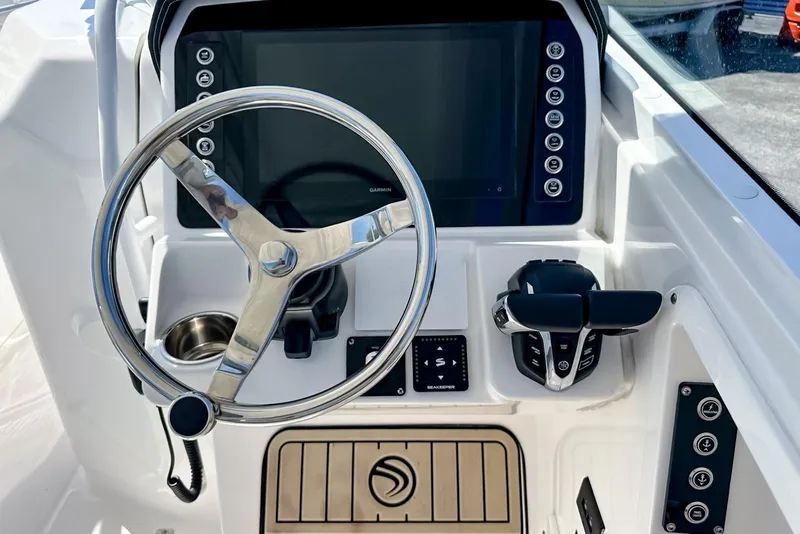 Slide: The Image of 2025 Edgewater 262 CX boat interior with white seating, dockside view, and waterfront buildings. - 31