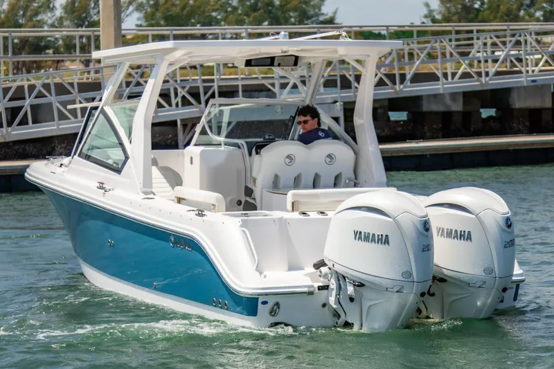 Slide: The Image of 2025 Edgewater 262 CX boat with dual Yamaha engines cruising in a marina. - 7