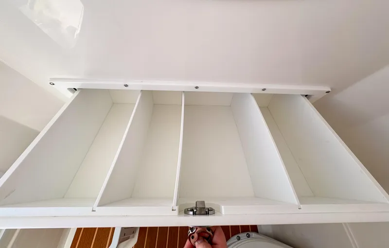 Slide: The Image of White storage compartment with dividers in 2025 Edgewater 325CC boat interior. - 12