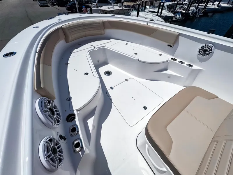 Slide: The Image of 2025 Edgewater 325CC boat interior with beige seating and speakers, docked at a marina. - 24
