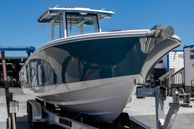 Slide: The Image of 2025 Edgewater 325CC boat on trailer, sleek design, blue hull, sunny day. - 5