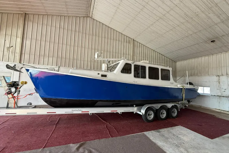 The Image of 2013 Eco-Trawler 33 boat in storage, blue hull, on a triple-axle trailer. - 0