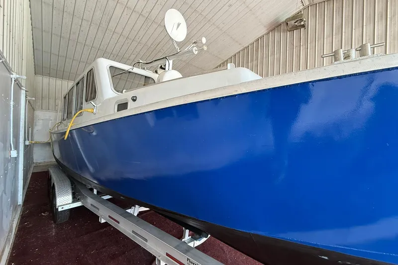 Slide: The Image of 2013 Eco-Trawler 33 in storage, featuring a sleek blue hull and white cabin. - 2