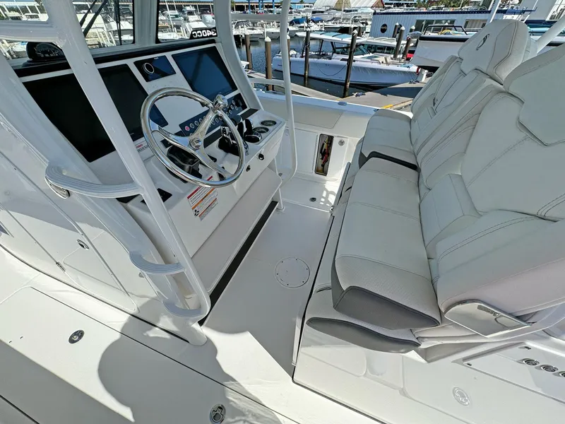 Slide: The Image of 2025 Edgewater 340CC boat interior with steering wheel and seating at marina. - 13