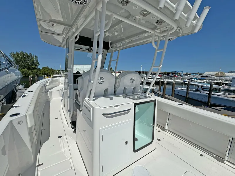 Slide: The Image of 2025 Edgewater 340CC boat interior at marina, showcasing seating and storage features. - 19