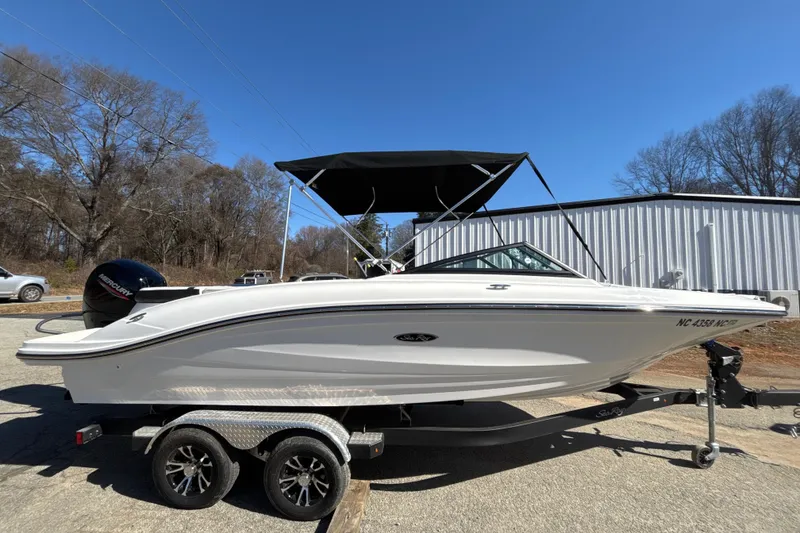 Slide: The Image of 2023 Sea Ray SPX 210 Outboard boat on trailer, parked outdoors under clear blue sky. - 2