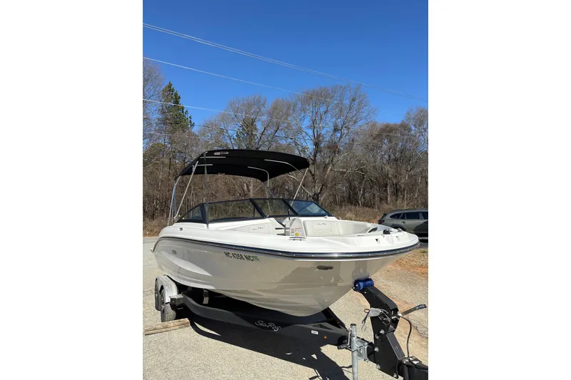 Slide: The Image of 2023 Sea Ray SPX 210 Outboard boat on trailer, parked outdoors under clear blue sky. - 4