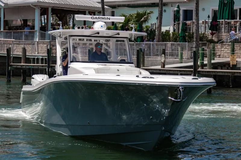Slide: The Image of 2025 Edgewater 370CC boat cruising near a dockside restaurant. - 4