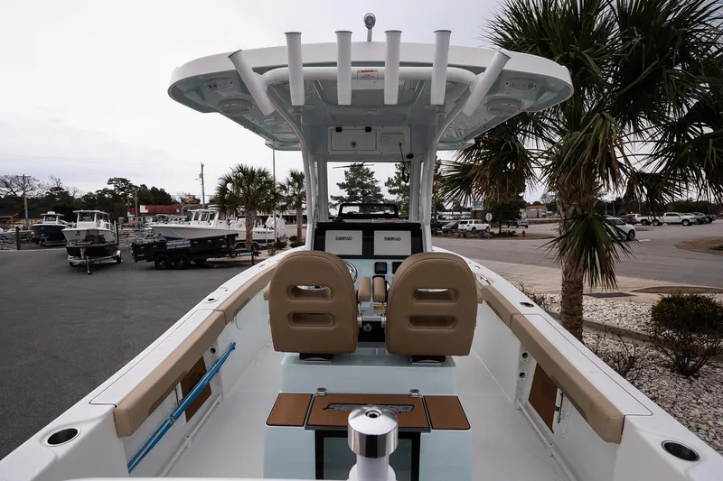 Slide: The Image of 2026 Sea Pro 245FLXR Sandbar boat interior with helm, seats, and palm trees in the background. - 6