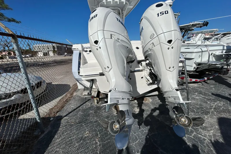 Slide: The Image of 2026 Robalo R250 Center Console with twin 150 horsepower outboard engines, parked outdoors. - 12
