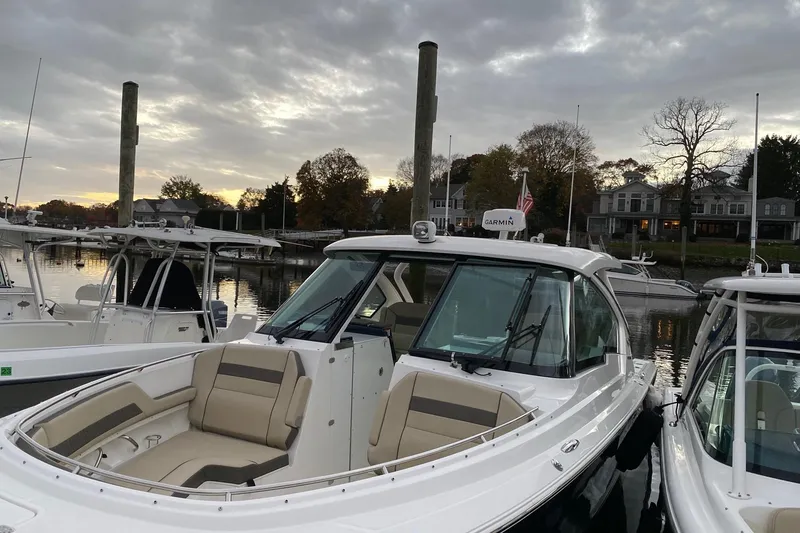 Slide: The Image of 2021 Pursuit DC 326 Dual Console boat docked at marina during sunset. - 2