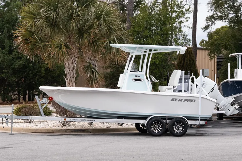 The Image of 2026 Sea Pro 202 Center Console boat on trailer, parked near palm trees. - 1