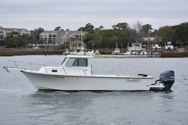 Slide: The Image of 2015 Parker 2320 SL Sport Cabin boat on water near marina, overcast sky. - 4