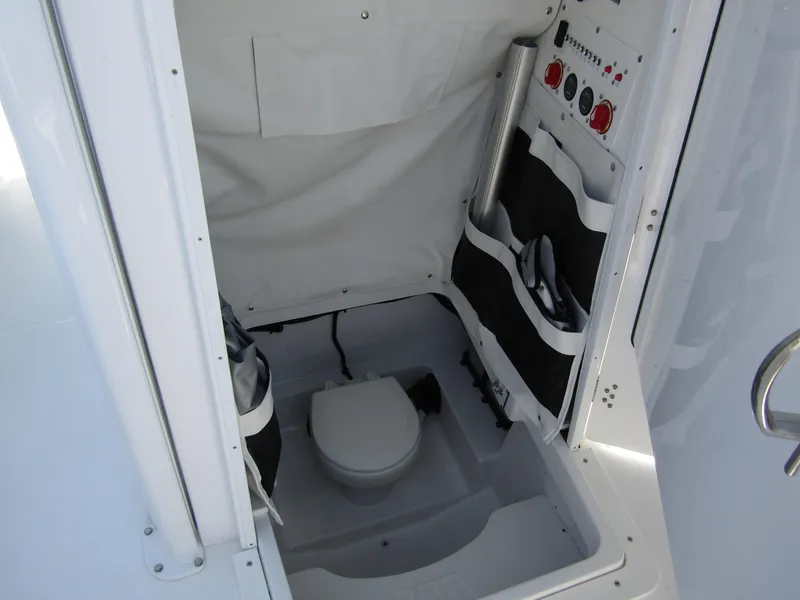 Slide: The Image of 2024 Wellcraft 243 Fisherman boat interior with compact marine toilet and storage compartments. - 17