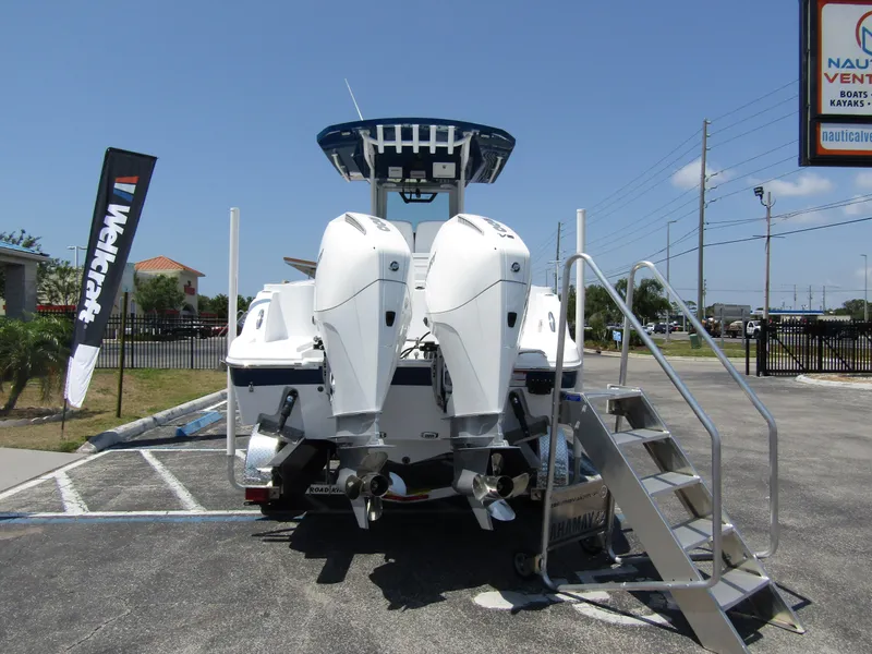 Slide: The Image of 2024 Wellcraft 243 Fisherman boat with twin outboard engines in a parking lot. - 2