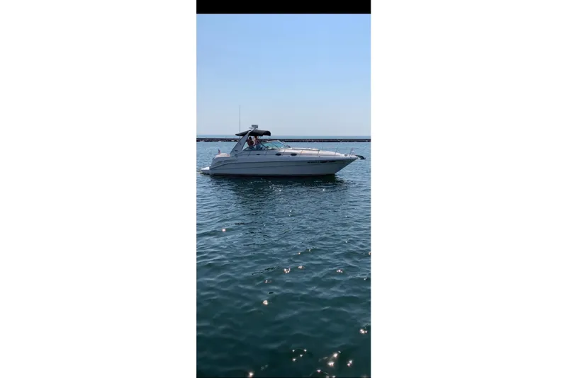 The Image of 2002 Sea Ray 340 Sundancer yacht cruising on calm blue waters. - 1
