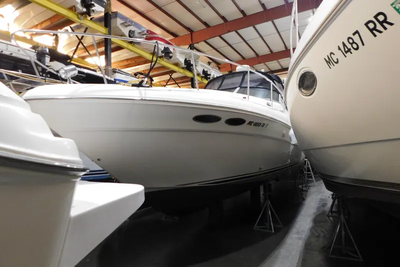 Slide: The Image of 2002 Sea Ray 340 Sundancer yacht in indoor storage, surrounded by other boats. - 2