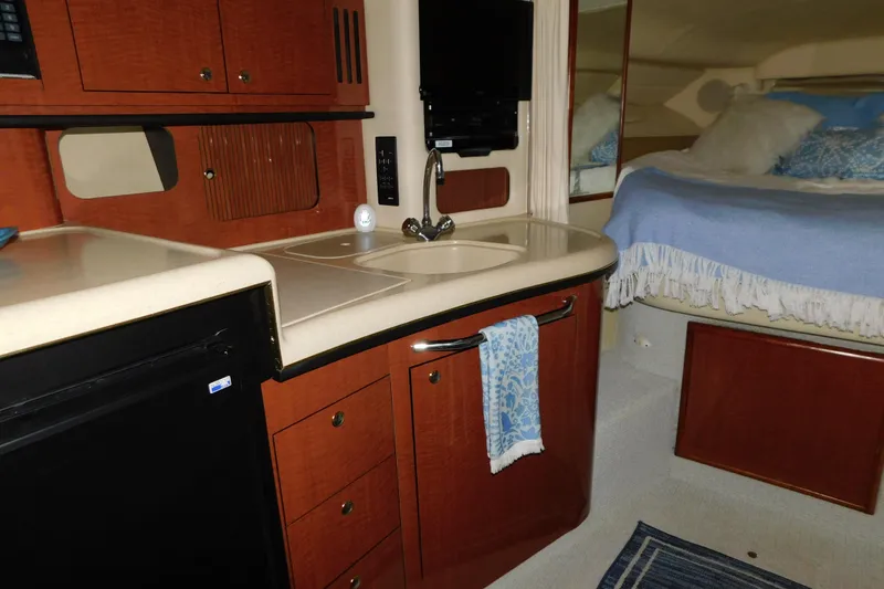 Slide: The Image of 2002 Sea Ray 340 Sundancer interior with kitchenette and cozy sleeping area. - 21