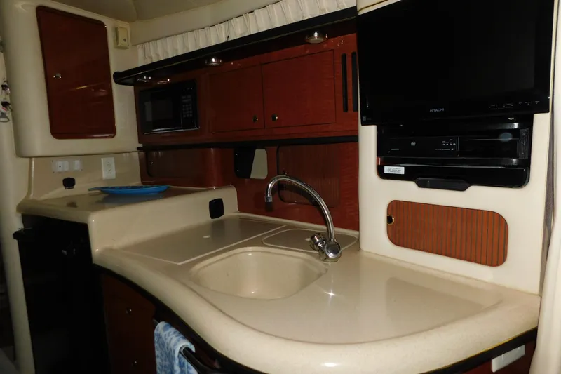 Slide: The Image of 2002 Sea Ray 340 Sundancer interior kitchen with sink, microwave, and TV. - 22