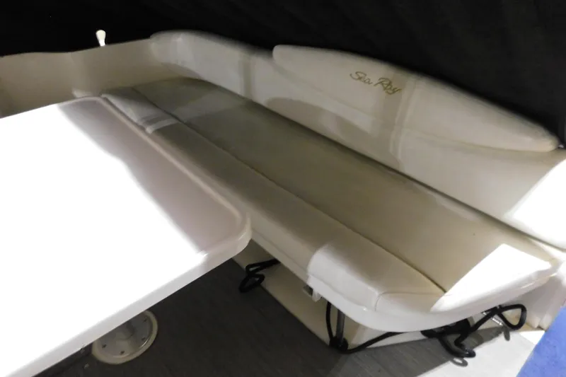 Slide: The Image of 2002 Sea Ray 340 Sundancer interior seating with table, showcasing comfortable white upholstery. - 6