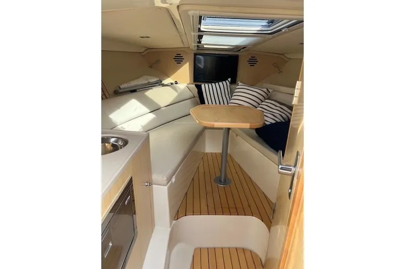 Slide: The Image of 2017 Chris-Craft Corsair 32 cabin interior with seating, table, and striped cushions. - 10