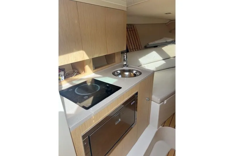 Slide: The Image of 2017 Chris-Craft Corsair 32 interior kitchen with stove, sink, and wooden cabinetry. - 11