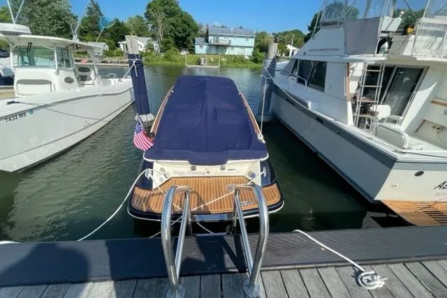 Slide: The Image of 2017 Chris-Craft Corsair 32 docked between boats, covered with a navy blue tarp. - 28