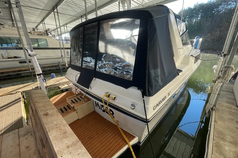 Slide: The Image of 1990 Carver 32 Montego boat docked under a covered marina, featuring a black canopy. - 13