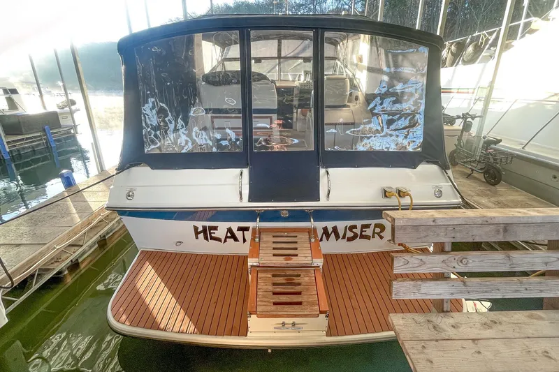 Slide: The Image of 1990 Carver 32 Montego boat docked, featuring wooden deck and covered seating area. - 14