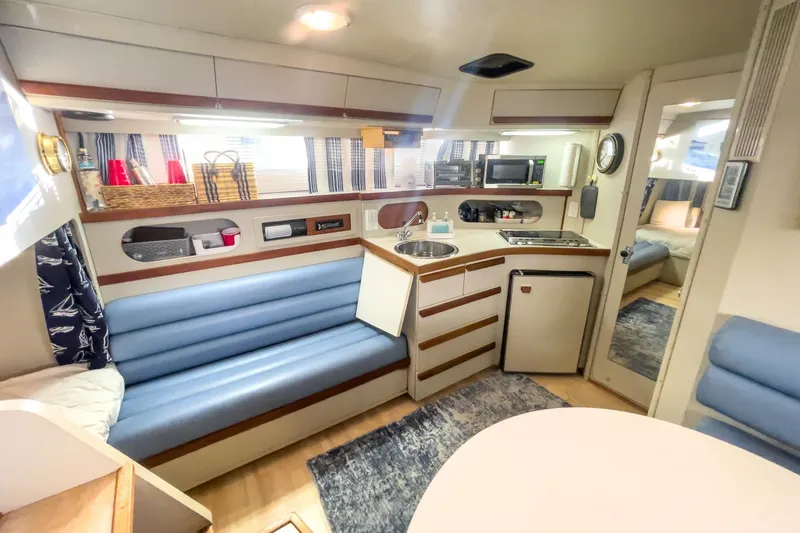 Slide: The Image of Interior of a 1990 Carver 32 Montego boat, featuring a cozy kitchen and seating area. - 28