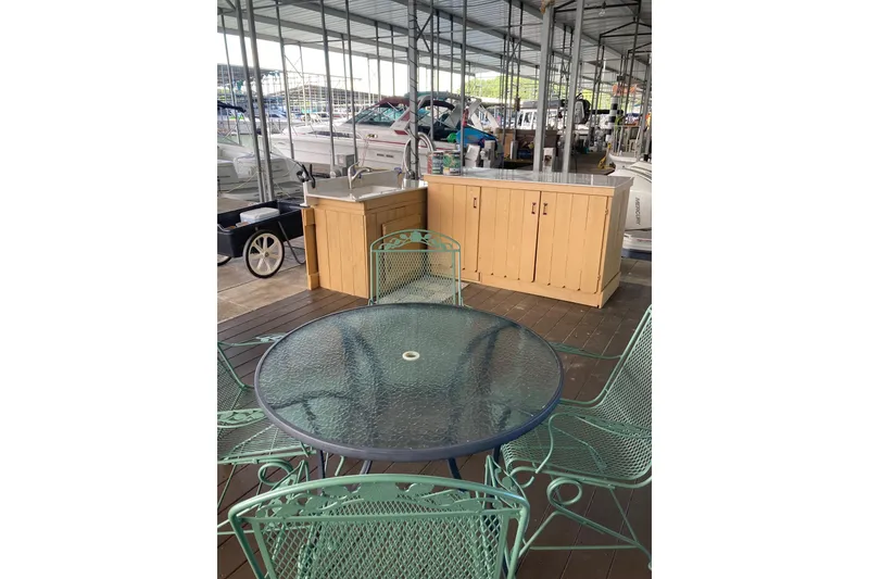 Slide: The Image of Outdoor marina setup with glass table, chairs, and Carver 32 Montego boat in background. - 45