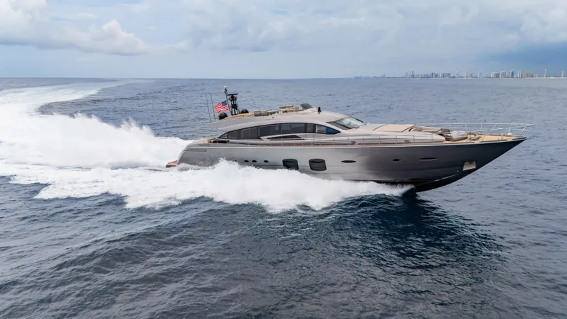 Slide: The Image of 2021 Pershing 108 yacht cruising on open sea with city skyline in background. - 21