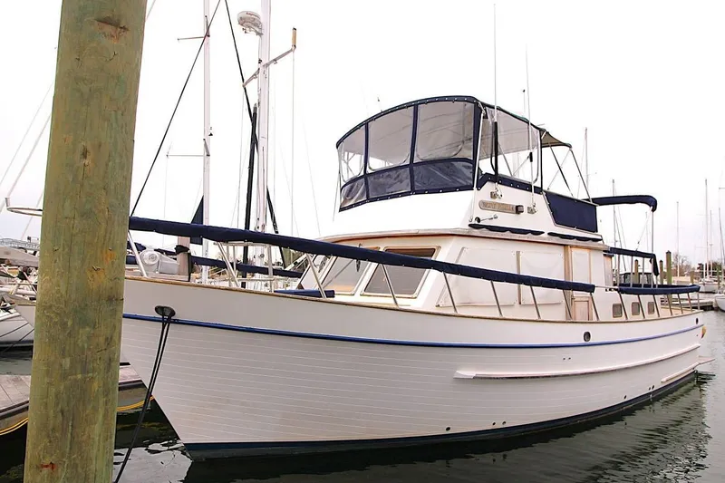 The Image of 1986 DeFever 41 Trawler docked at marina, featuring classic design and blue canopy. - 0