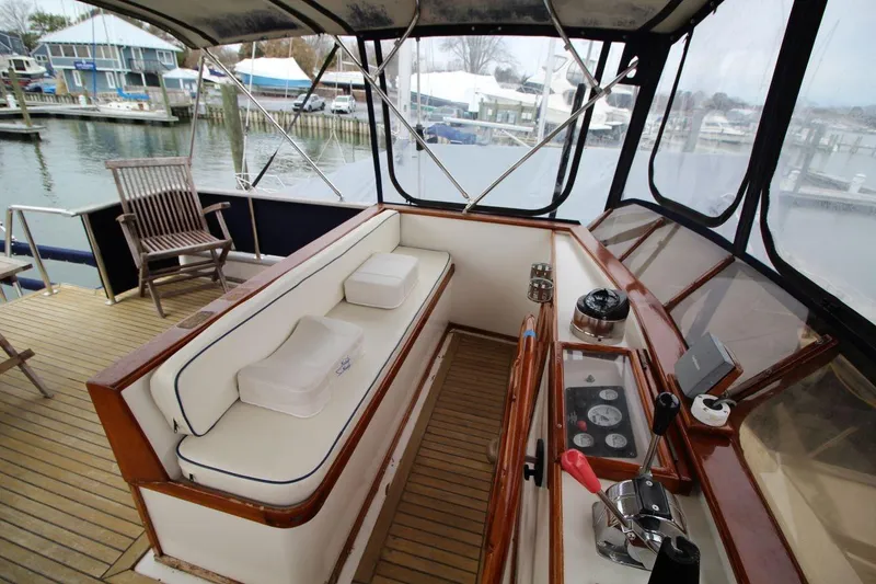 Slide: The Image of 1986 DeFever 41 Trawler helm with seating, wooden accents, and marina view. - 13