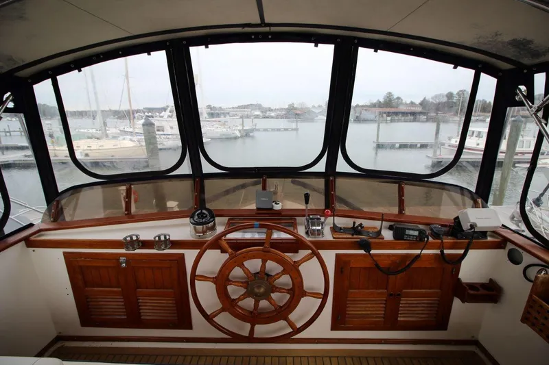 Slide: The Image of 1986 DeFever 41 Trawler helm with wooden wheel and marina view. - 15