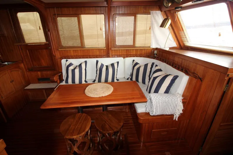 Slide: The Image of 1986 DeFever 41 Trawler interior with wooden decor, striped cushions, and cozy seating area. - 20