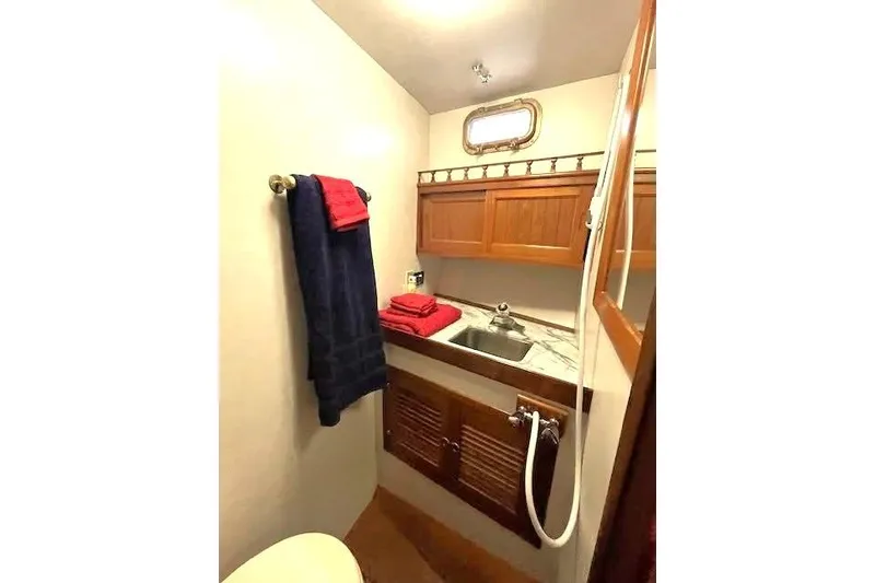 Slide: The Image of 1986 DeFever 41 Trawler bathroom with wooden cabinets and marble countertop. - 28