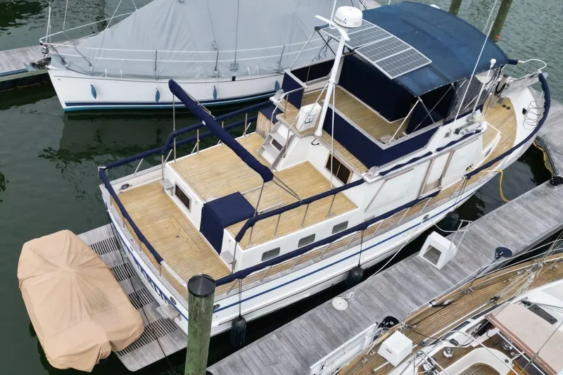 Slide: The Image of 1986 DeFever 41 Trawler docked, featuring spacious deck and solar panels. - 6