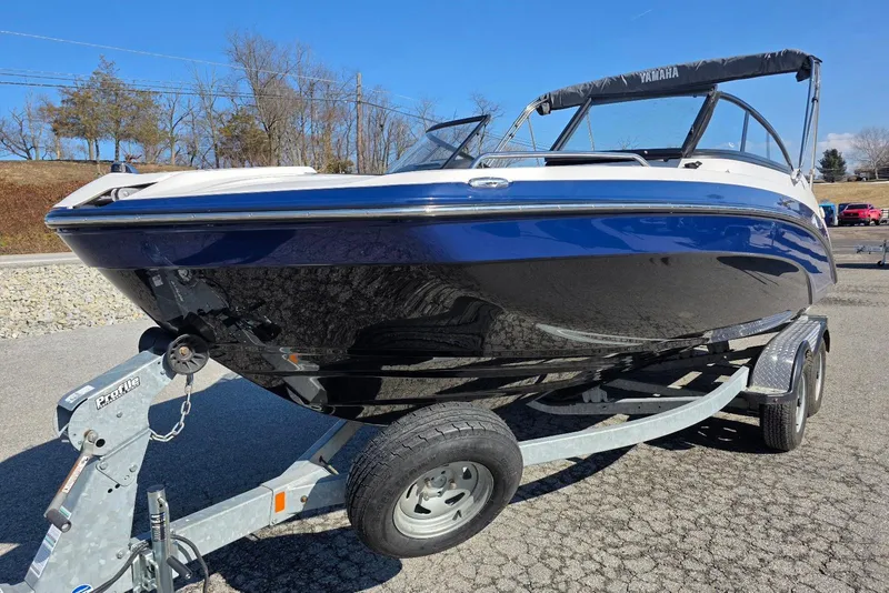 Slide: The Image of 2017 Yamaha Boats 212 Limited on trailer, blue and white exterior, parked outdoors. - 6