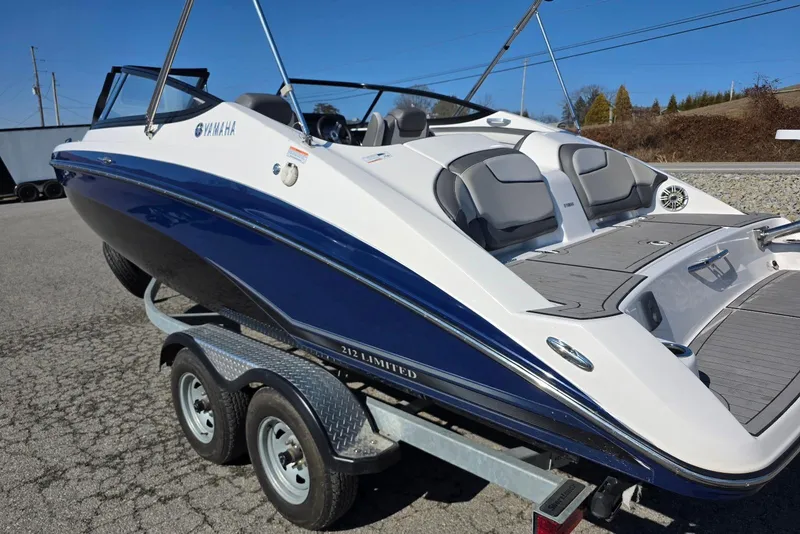 Slide: The Image of 2017 Yamaha Boats 212 Limited on trailer, sleek design, blue and white exterior. - 8